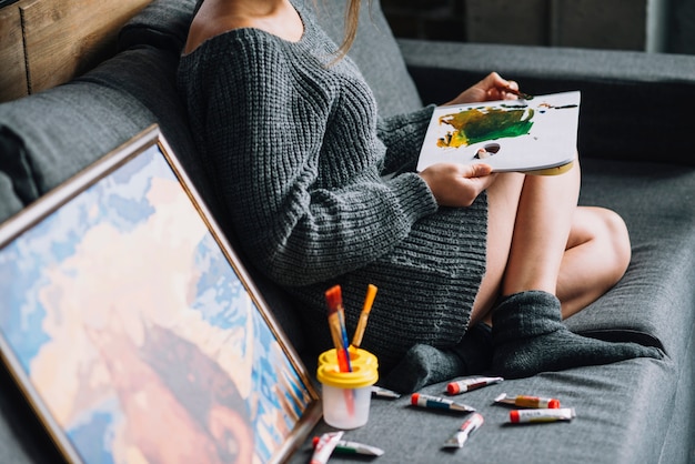 Femme peinture sur le canapé à côté de la peinture