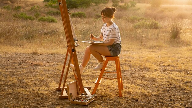 Femme peinture sur toile à l'extérieur dans la nature