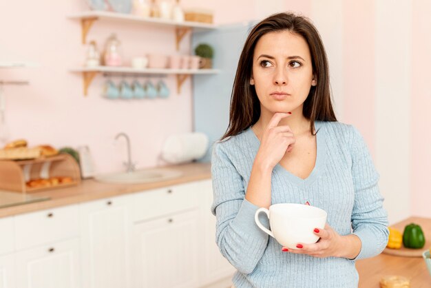 Femme pensant coup moyen avec tasse blanche