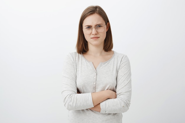 Femme pensant mec couché regardant suspect avec incrédulité. Intense mal sûr jeune femme européenne intelligente à lunettes fronçant les sourcils tenant les mains croisées sur la poitrine mécontent de penser que parler est des conneries