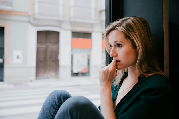 Femme pensant près de la fenêtre de café