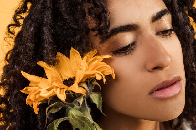 Femme pensive ethnique sensuelle avec fleur