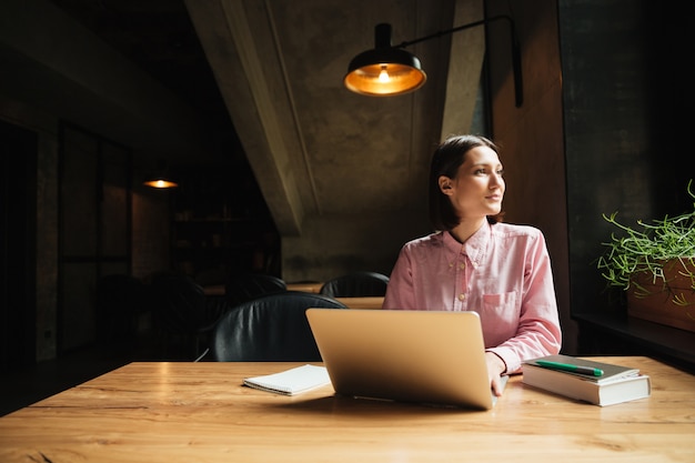 Femme pensive insouciante assise près de la table au café