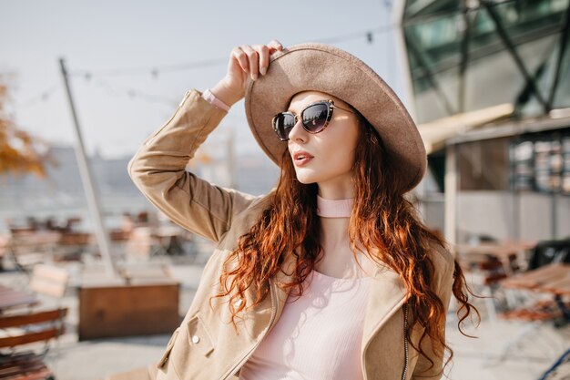 Femme pensive avec de longs cheveux bruns regardant, ami en attente à côté de café en plein air