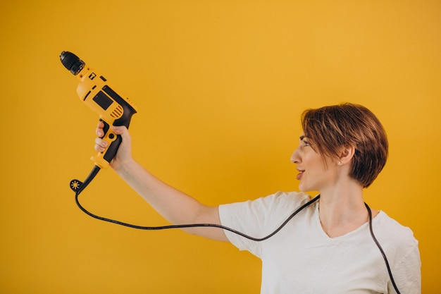 Photo gratuite femme avec perceuse électrique sur fond jaune