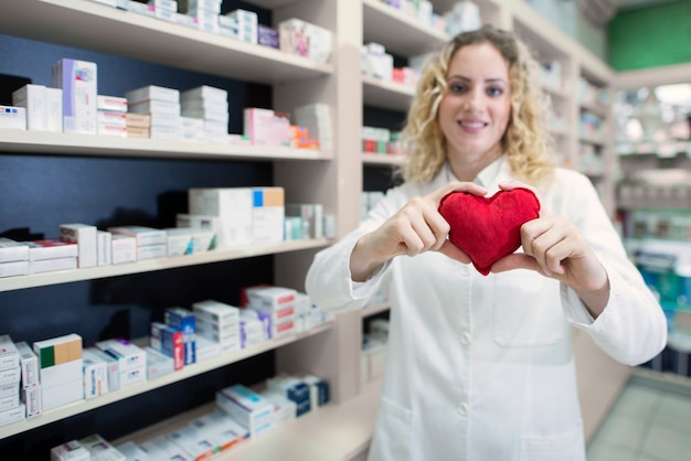 Femme pharmacien tenant coeur et faisant la promotion des médicaments cardiovasculaires et du traitement réussi