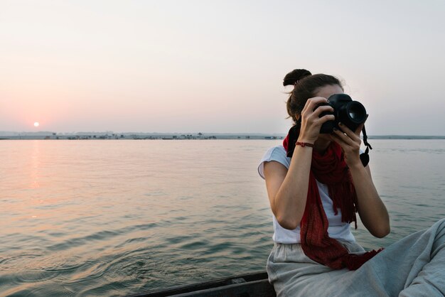 Femme photographe assise sur un bateau sur le Gange