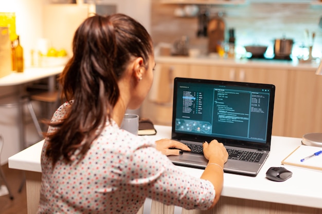 Femme pirate utilisant un virus dangereux pour voler des informations bancaires. Programmeur écrivant un logiciel malveillant pour les cyberattaques à l'aide d'un ordinateur portable performant à minuit.