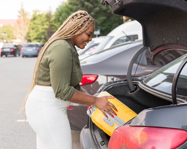 Photo gratuite femme plaçant ses bagages dans son coffre