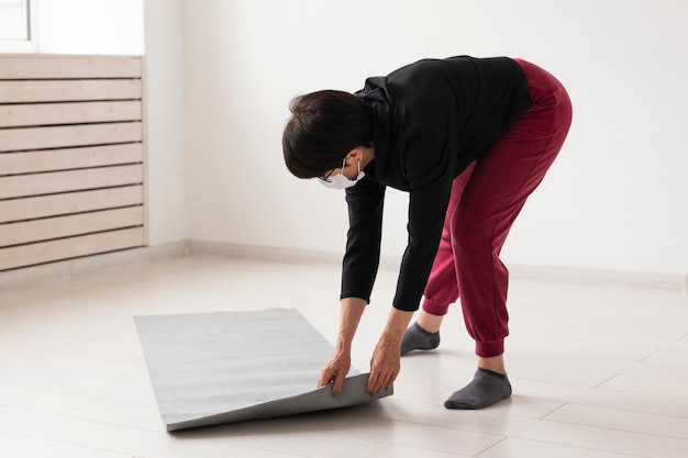 Photo gratuite femme plaçant un tapis de fitness sur le sol