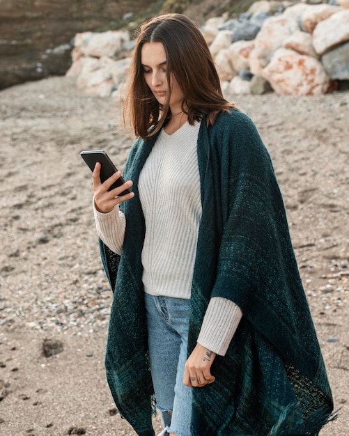 Femme à la plage à l'aide de smartphone