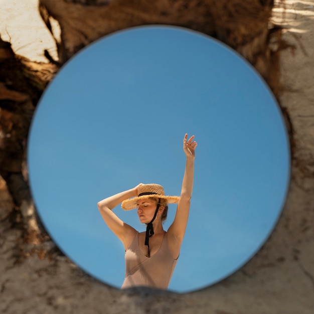 Femme à la plage en été posant avec miroir rond