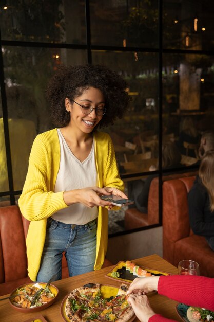 Femme de plan moyen prenant des photos de nourriture