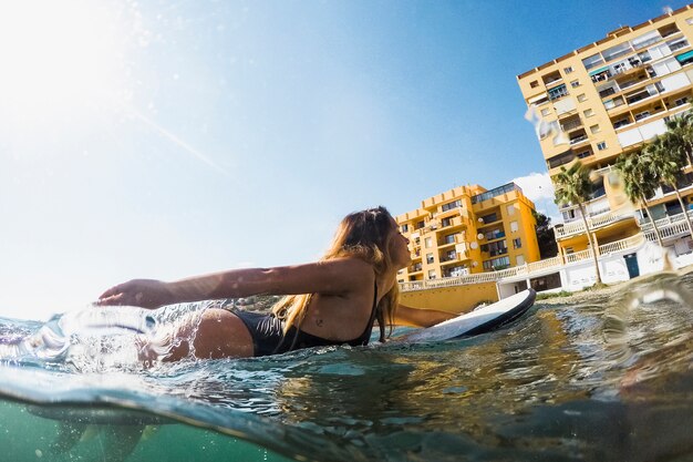 Femme avec planche de surf dans l&#39;eau