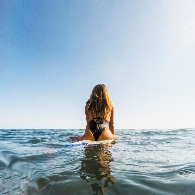 Femme avec planche de surf dans l&#39;eau