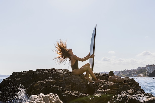 Femme avec planche de surf à la plage