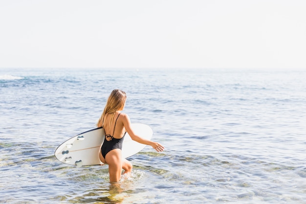 Femme avec planche de surf à la plage