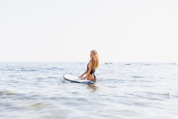 Femme avec planche de surf à la plage