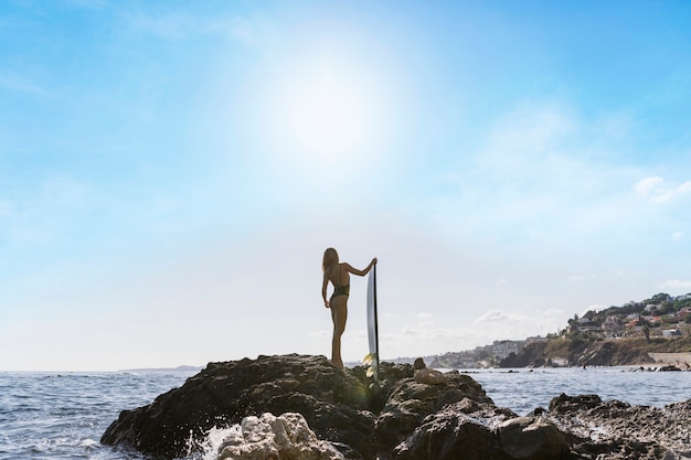 Femme avec planche de surf à la plage