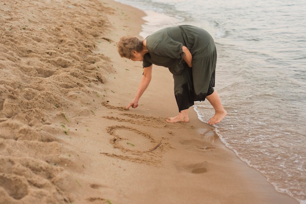 Femme plein coup écrit sur le sable