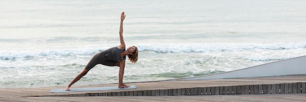 Femme de plein coup faisant le triangle pose sur la plage