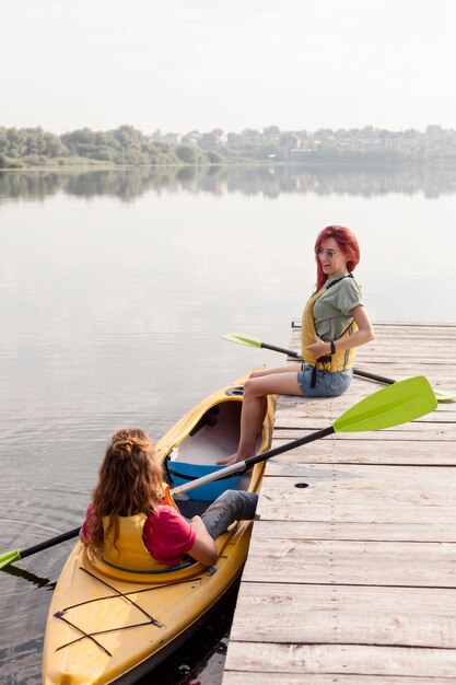 Femme plein coup en kayak avec un ami sur le quai