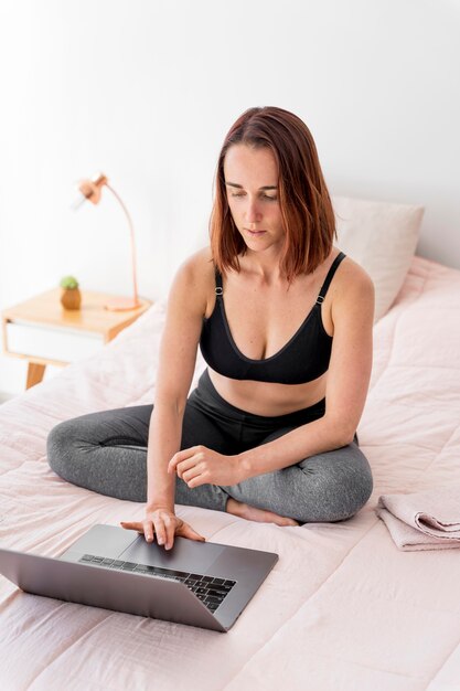 Femme plein coup avec ordinateur portable au lit