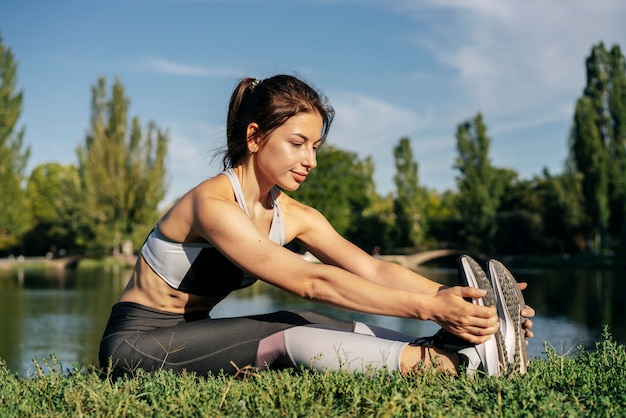 Femme plein coup qui s'étend dans le parc