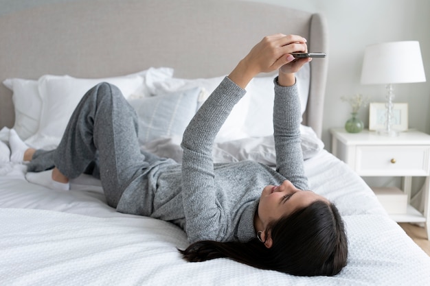 Femme plein coup avec smartphone au lit