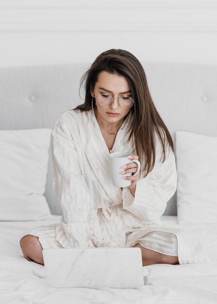 Femme plein coup avec tasse et ordinateur portable