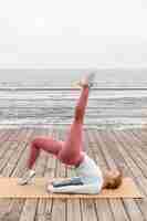 Photo gratuite femme pleine de coups faisant du yoga au bord de la mer