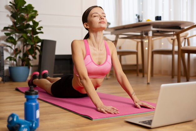 Femme pleine de coups faisant du yoga à l'intérieur