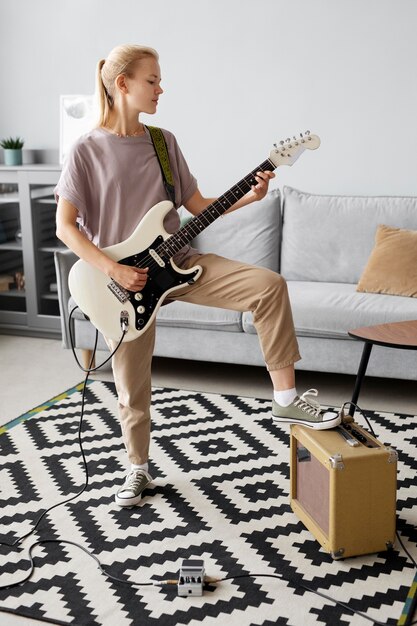 Femme pleine de coups jouant de la guitare à la maison