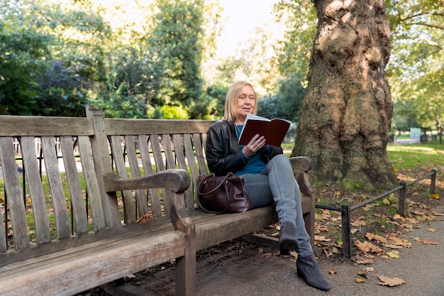 Femme pleine de coups lisant dans le parc