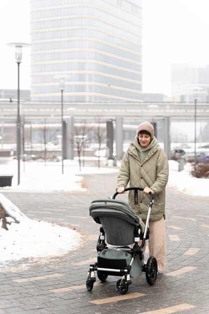 Femme pleine de coups avec poussette à l'extérieur