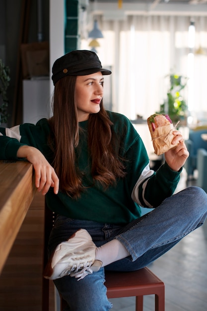 Une femme pleine avec un sandwich enveloppé en papier.