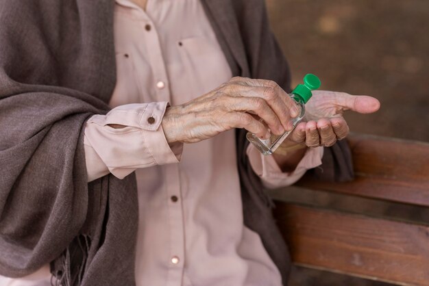 Femme plus âgée à l'aide d'un désinfectant pour les mains