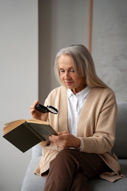 Femme plus âgée à l'aide d'une loupe pour lire