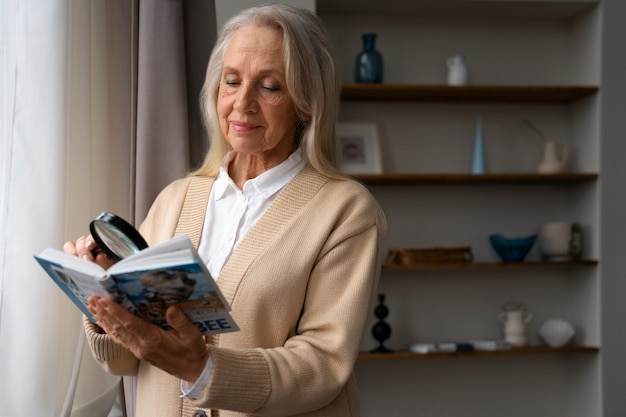 Photo gratuite femme plus âgée à l'aide d'une loupe pour lire