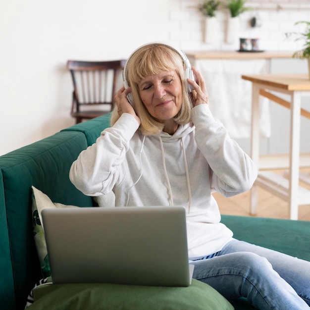 Femme plus âgée, écouter de la musique à l'aide d'un casque et d'un ordinateur portable