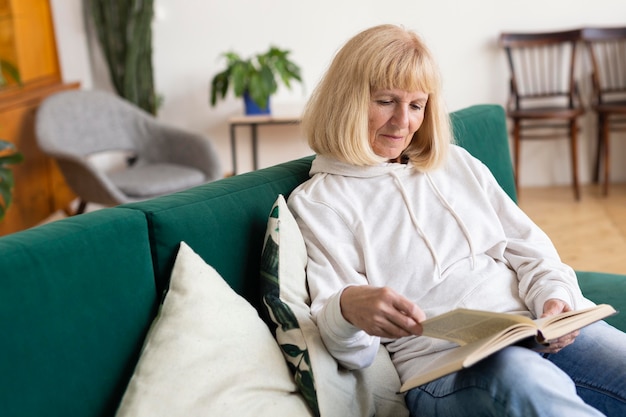 Photo gratuite femme plus âgée à la maison sur le canapé en lisant un livre