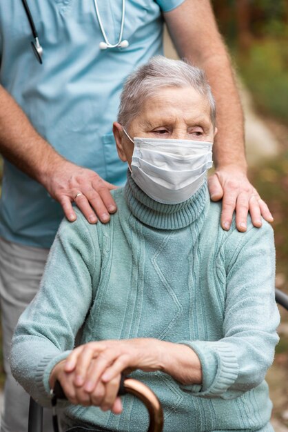 Femme plus âgée avec masque médical et infirmier à la maison de soins infirmiers