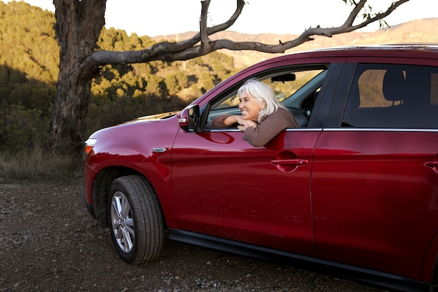 Une femme plus âgée part à l'aventure dans la nature avec sa voiture