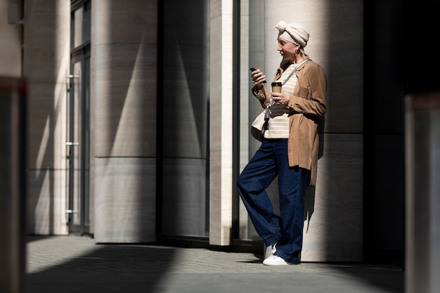 Femme plus âgée utilisant un smartphone à l'extérieur de la ville