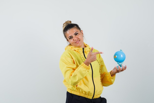 Femme pointant sur le globe de l'école en costume de sport et à la vue de face positive