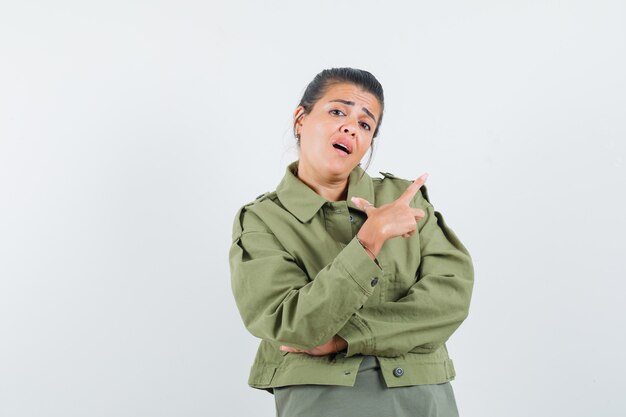 femme pointant vers le coin supérieur droit en veste, t-shirt et à la confiance.