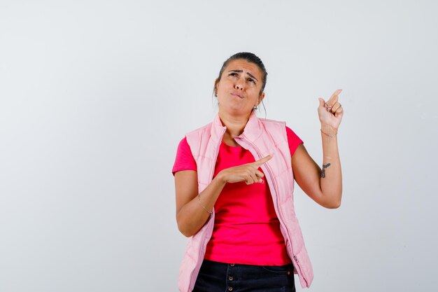 Femme pointant vers le haut en t-shirt, gilet et à la triste