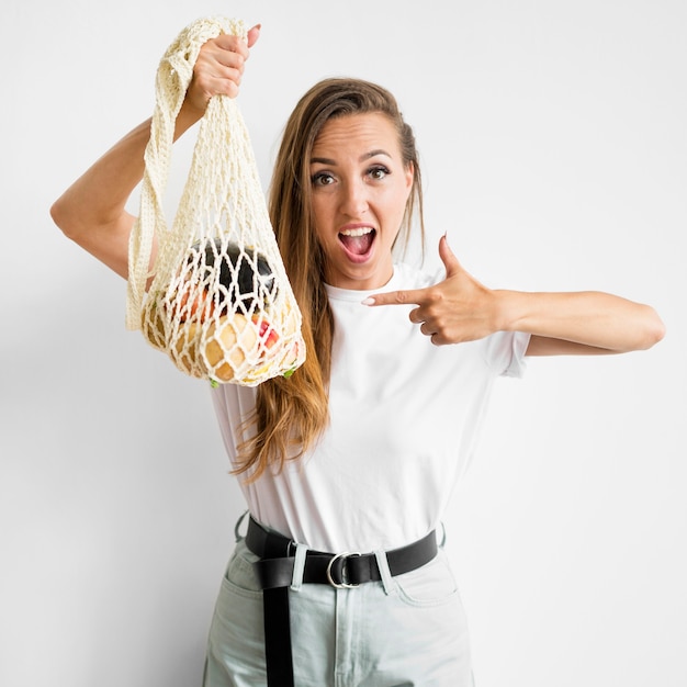 Photo gratuite femme pointant vers un sac avec des goodies sains