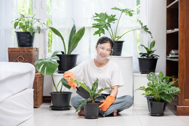La femme portait des gants orange et plantait des arbres dans la maison.