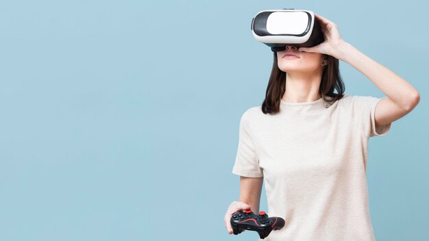 Femme portant un casque de réalité virtuelle et tenant la télécommande